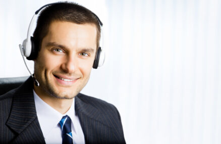Portrait of happy smiling customer support phone operator in headset at office. You can use right part for slogan, text or banner.